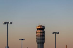 AN AIR TRAFFIC CONTROL TOWER IS SILHOUETTED AGAINST A SUNSET SKY