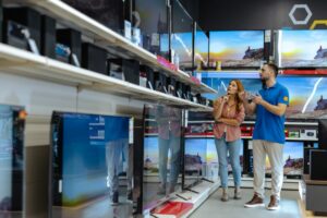 Woman receiving assistance from store employee in electronics section