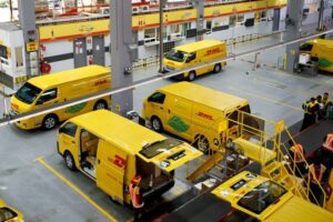 A DOZEN BRIGHT YELLOW VANS ARE ARRAYED IN A DISTRIBUTION CENTER, SEEN FROM ABOVE