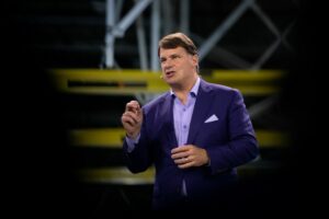 A MAN IN A BLUE SUIT ADDRESSES AN AUDIENCE