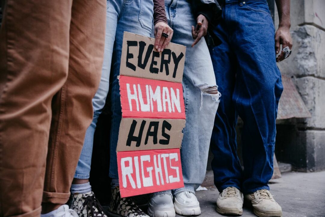 Group of people marching for human rights, holding a sign that reads every human has rights
