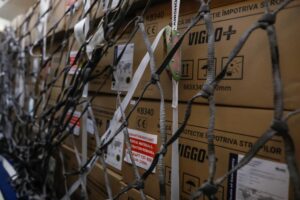 Stacks of brown cardboard boxes sitting in the cargo hold of an airplane, contained with grey and black netting