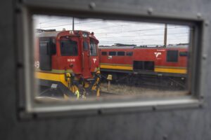 Two red freight trains parked in a trainyard on a cloudy day