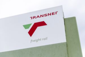 The corner of a large white building with a green and red "T" logo and "Transnet" written in red above it