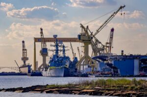 A LARGE SHIP SITS AT DOCK AT A SHIPBUILDING YARD