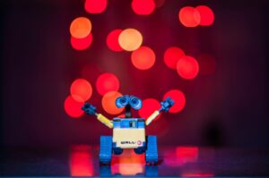 A SMALL ROBOT WITH EXPRESSIVE, ANXIOUS EYES, HOLDS ITS ARMS OUT IN SUPPLICATION.